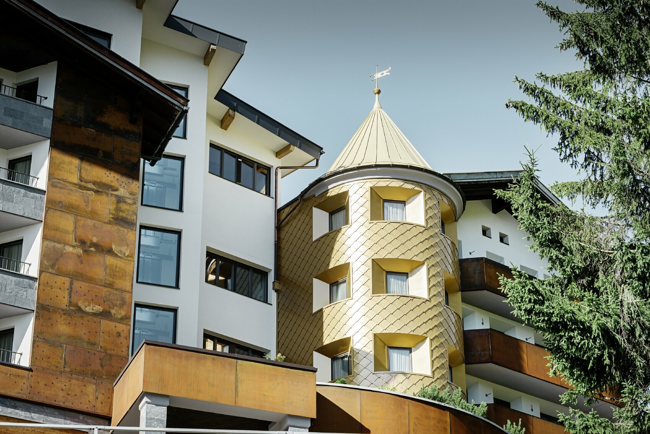 hotel tradizionale a Ischgl con balconi in legno e facciata in legno e una torre in scaglie PREFA in oro