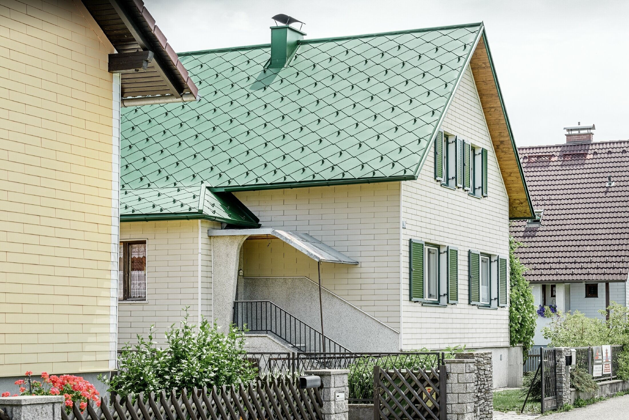 Casa unifamiliare classica con tetto a doppia falda con una copertura in alluminio in verde muschio con scuri verdi.