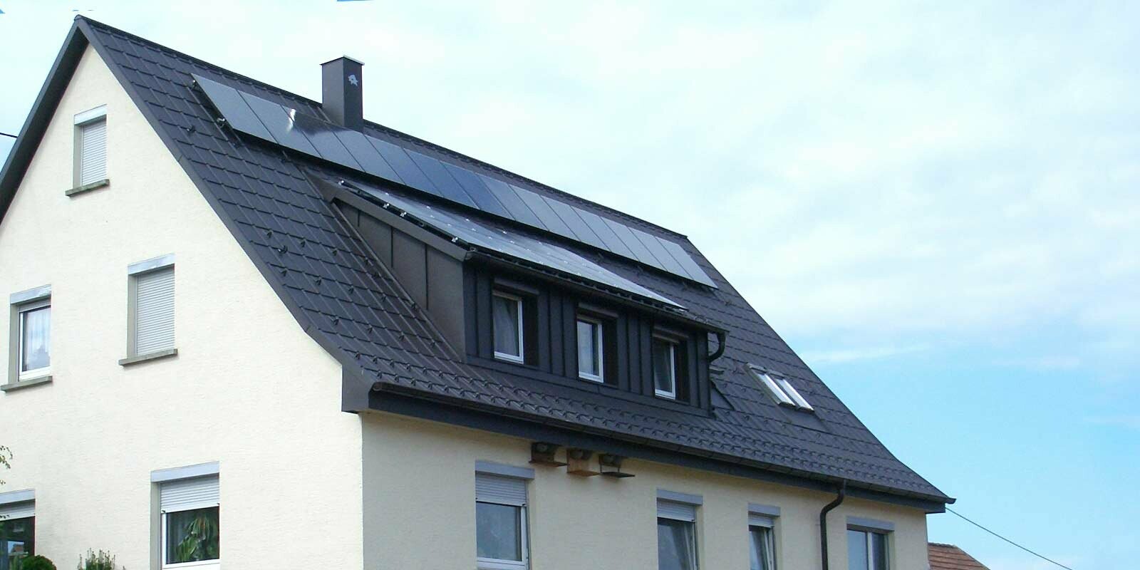 Toit récemment rénové à l’aide de tuiles PREFA couleur anthracite, la lucarne a été recouverte d’éléments Prefalz. Le toit est pourvu d’une installation photovoltaïque.