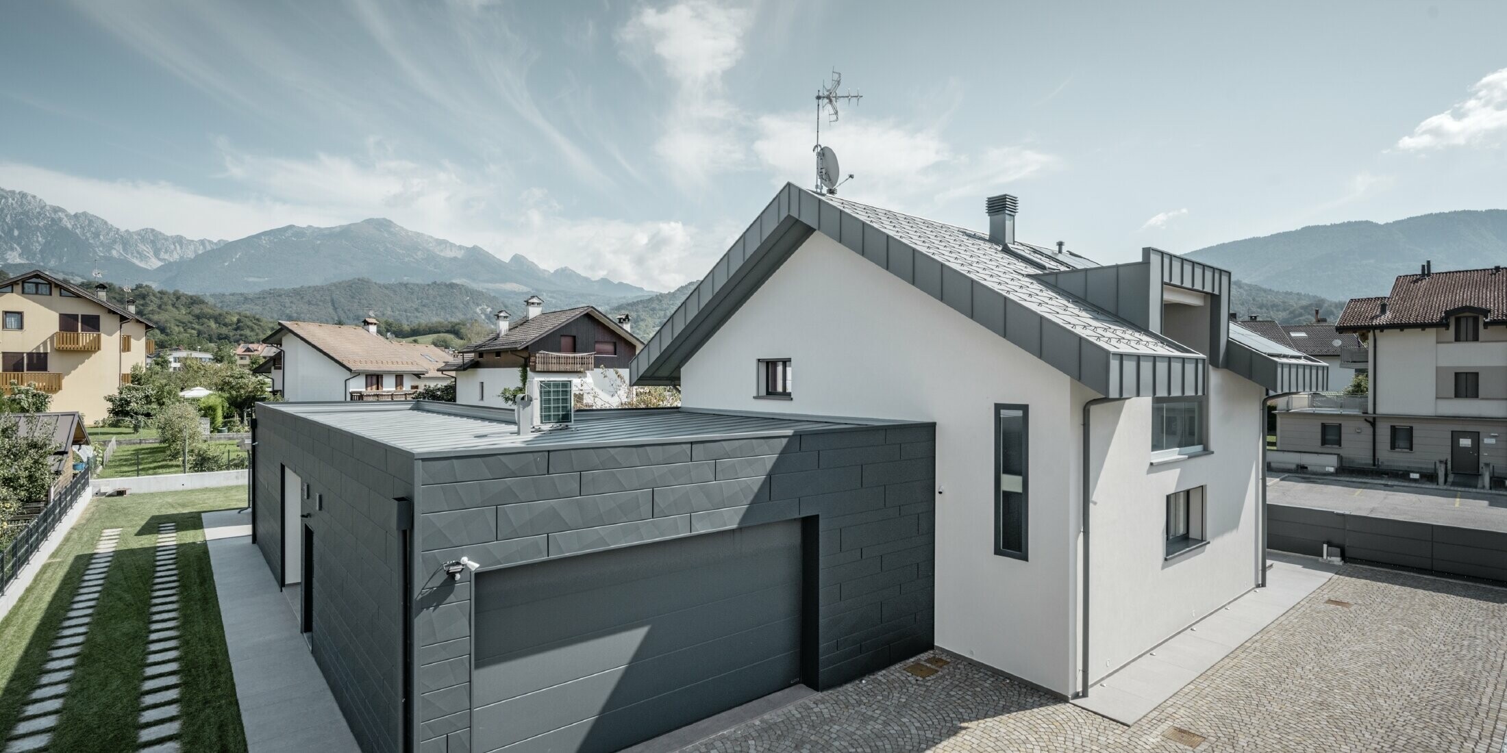 Photo de la maison individuelle, le garage est habillé de Siding.X tandis que le toit est recouvert de R.16 dans la couleur P.10 gris souris.