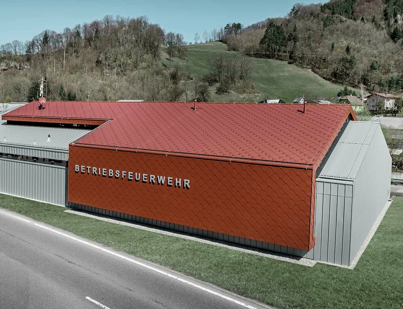 La nouvelle caserne des sapeurs-pompiers des entreprises PREFA et Neuman Aluminium a été habillée des nouveaux losanges de toiture et de façade 44 × 44 couleur P.10 rouge oxyde ainsi que de Prefalz argent métallisé.
