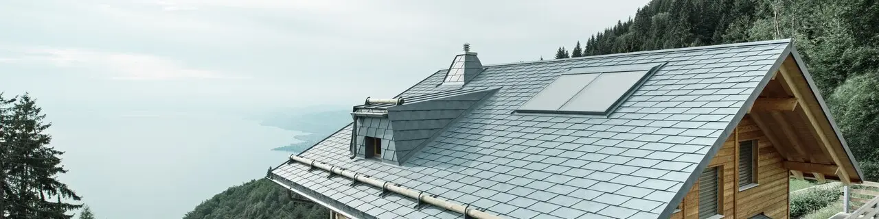Lodge Veytaux au bord du lac Léman en Suisse. La toiture en bardeaux PREFA robuste et durable, de couleur gris pierre, protège la maison dans les Alpes et se marie parfaitement avec la façade en bois.