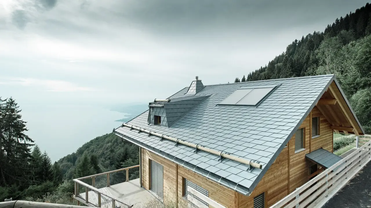Lodge Veytaux sul Lago di Ginevra in Svizzera. Il tetto in scandole PREFA, robusto e durevole, in grigio pietra protegge la casa nelle Alpi e si abbina perfettamente alla facciata in legno.