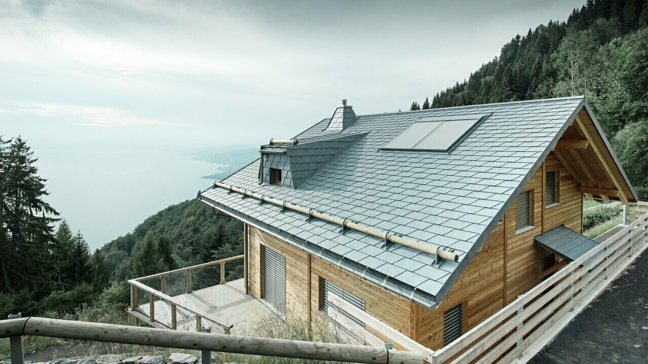 Lodge Veytaux am Genfersee in der Schweiz. Das robuste und langlebige PREFA Schindeldach in steingrau schützt das Haus in den Alpen und stellt eine perfekte Kombination mit der Holzfassade dar.