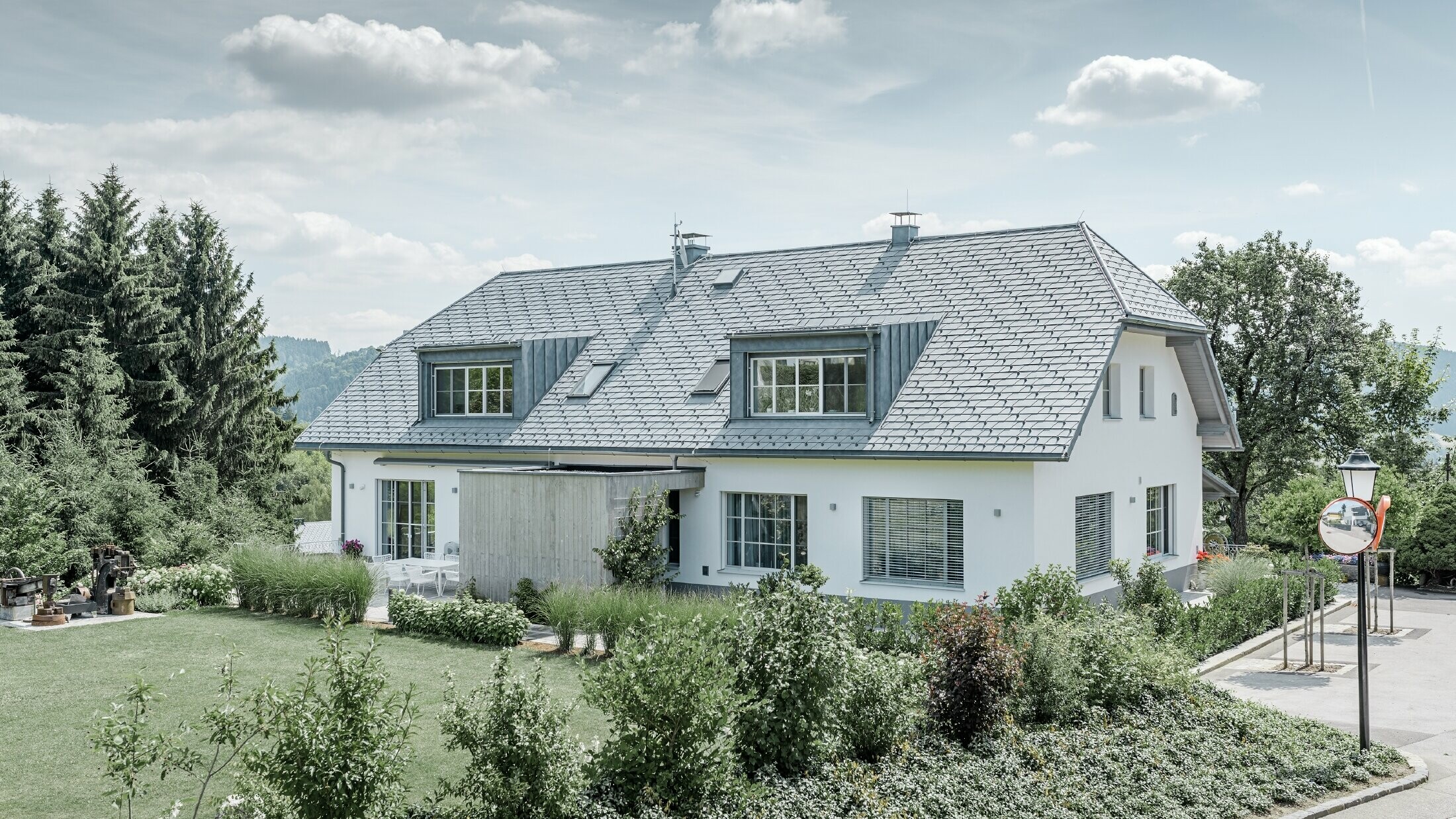 Rénovation d’un toit à demi croupe doté de deux lucarnes avec le léger bardeau de toiture PREFA couleur gris pierre.