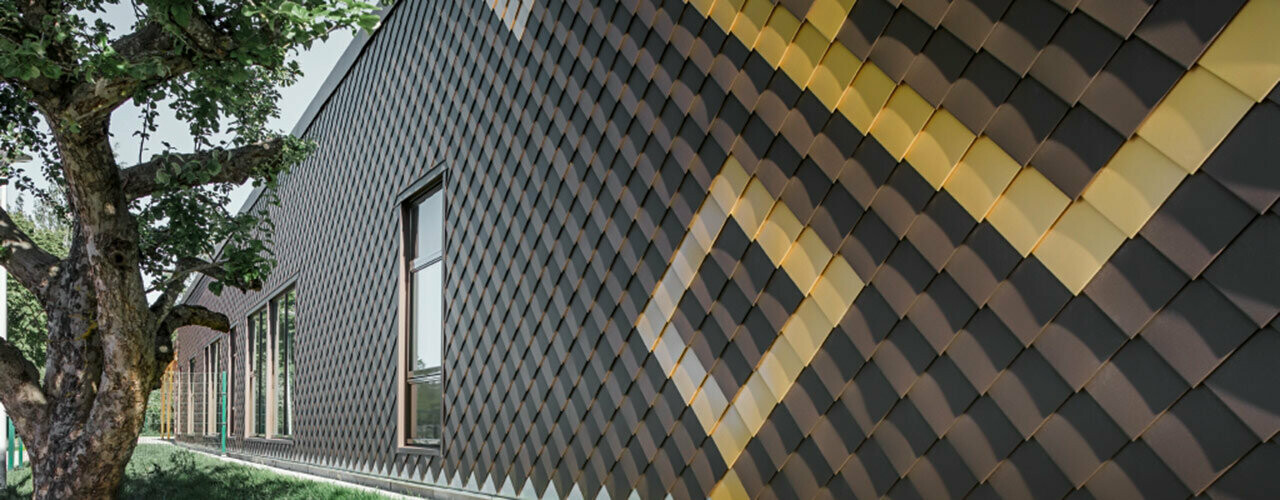 Facciata con losanghe PREFA marroni 20 x 20. Le losanghe a contrasto color oro creano un motivo sulla facciata.