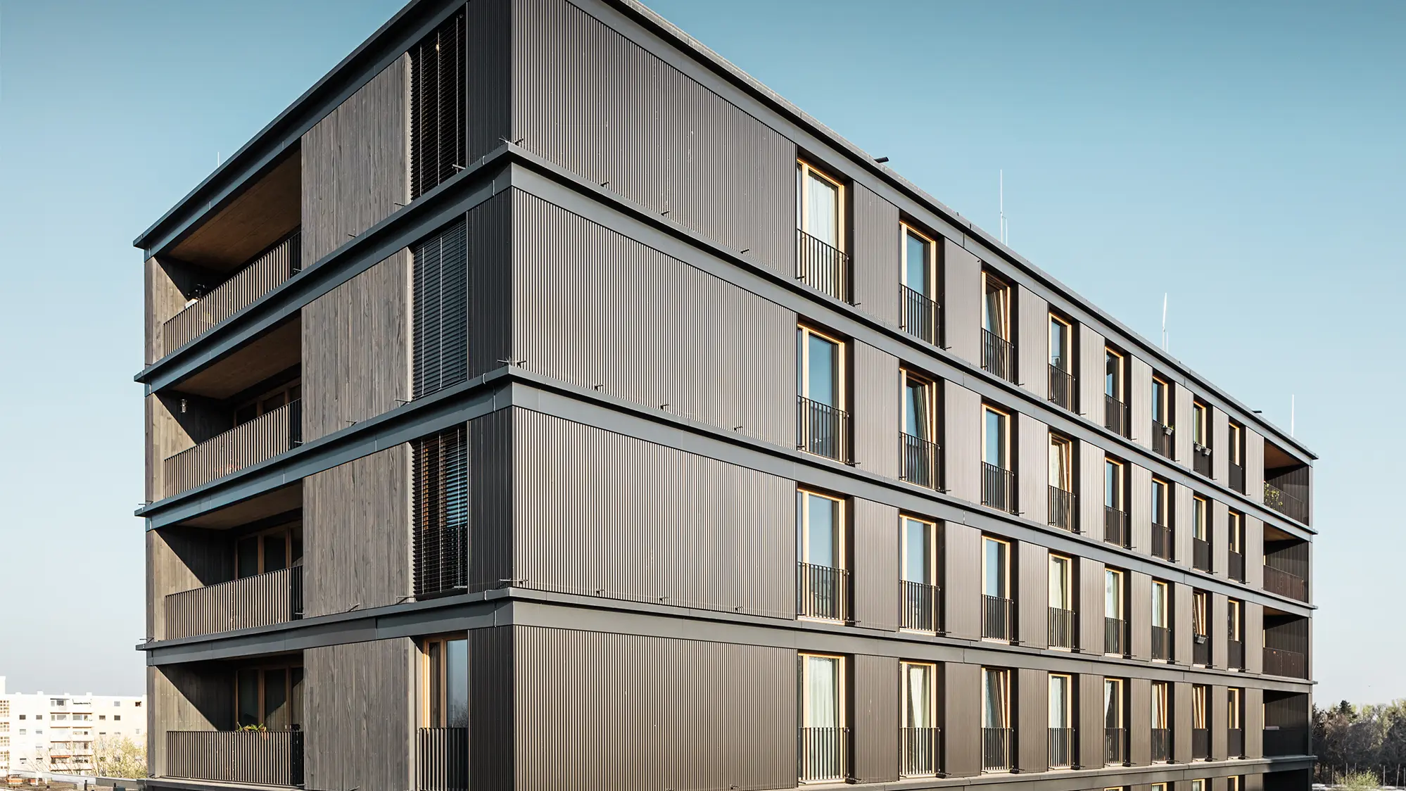  L'immeuble d'habitation et de bureaux vu de côté : le profil ondulé de PREFA et la façade en bois sont presque indiscernables.