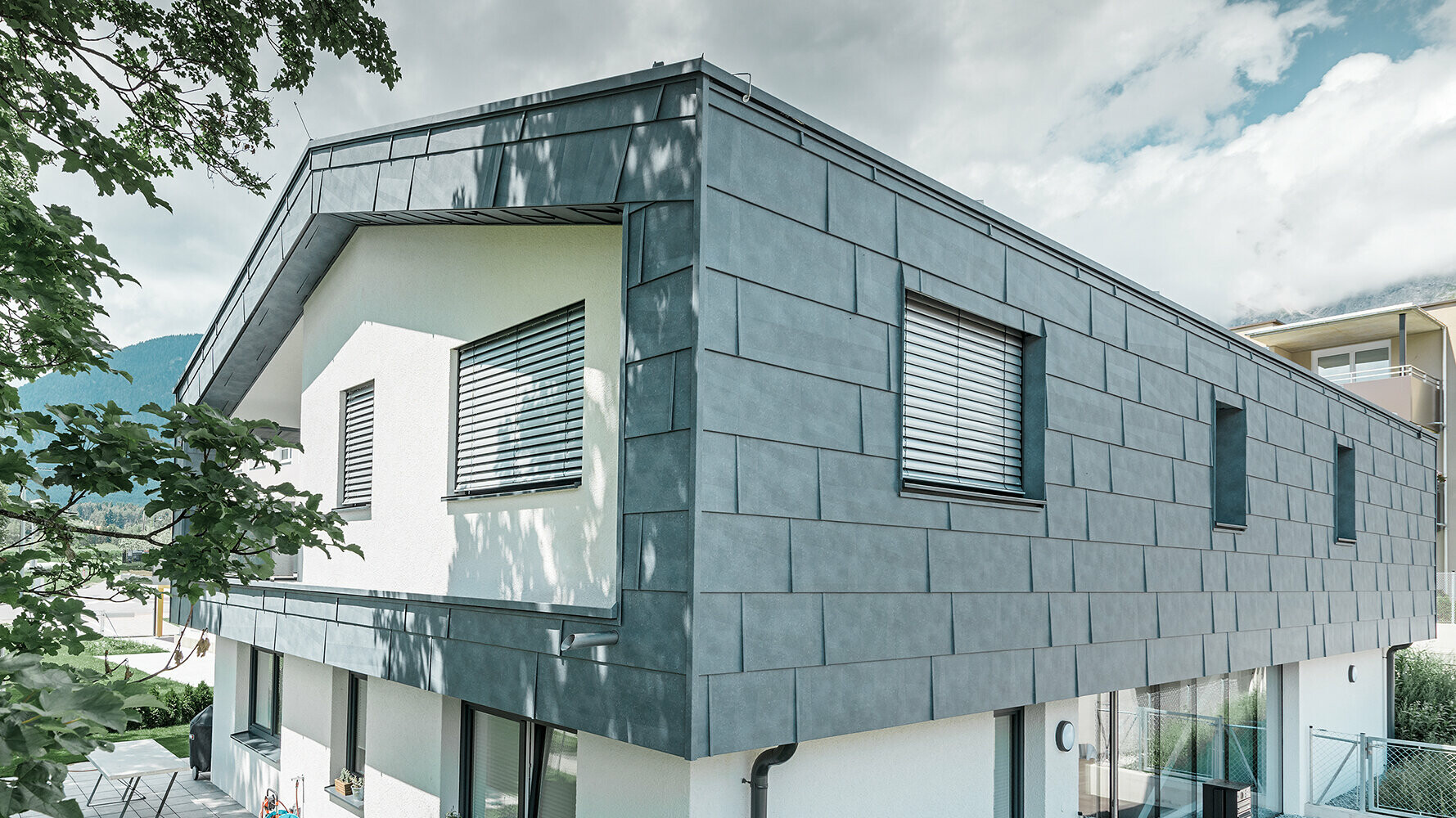 Moderna casa unifamiliare senza centina; il piano superiore è stato rivestito con i pannelli per facciate FX.12 in grigio pietra, il resto della facciata è stato intonacato di bianco.