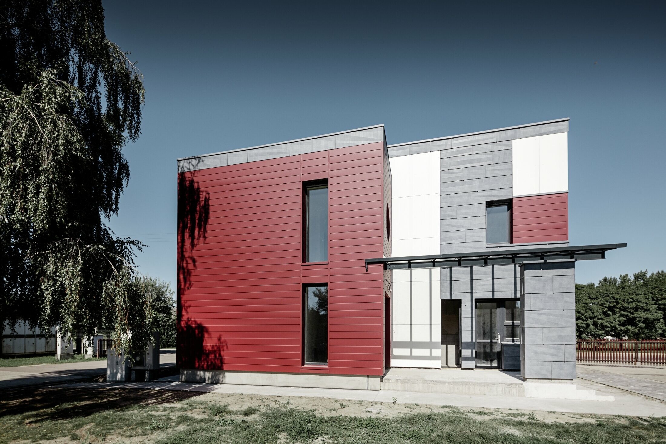 Uffici moderni con una facciata frazionata in rosso, grigio pietra e bianco con i prodotti doghe, pannello per facciata FX.12 e pannello composito di PREFA in alluminio 