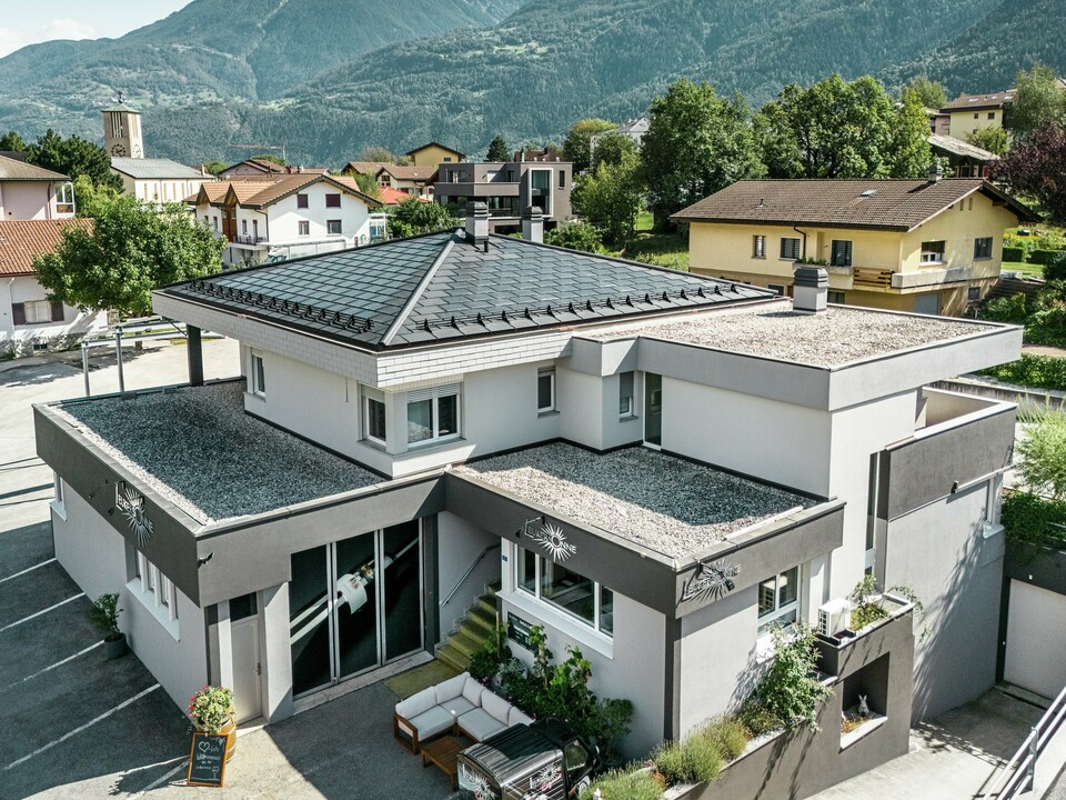 Das elegante PREFA Dach aus Aluminium verleiht der Weinkellerei Leukersonne in Susten (CH) ein modernes Erscheinungsbild und bietet optimalen Schutz vor Witterungseinflüssen. PREFA Solardachplatten sorgen für eine nachhaltige Energiegewinnung ohne das Erscheinungsbild des Zeltdaches zu beeinträchtigen. Abgerundet wird die Dachlandschaft durch PREFA Dachplatten R.16. Das erste Obergeschoss und der restliche Teil des zweiten Obergeschosses sind mit einem begehbaren Kiesbelag versehen. 