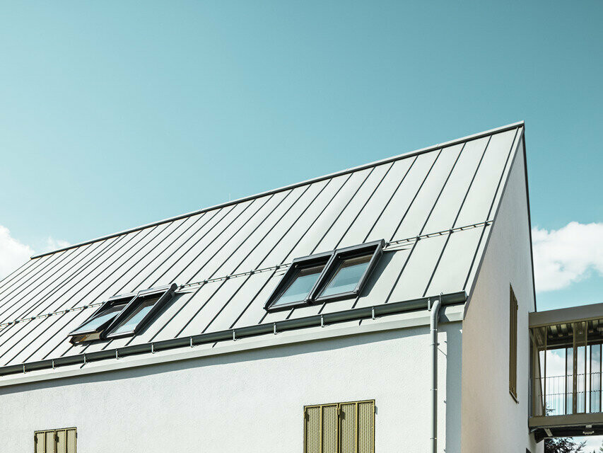 Vue latérale de la maison d'habitation recouverte de préfabriqué de la couleur P.10 gris zinc au soleil