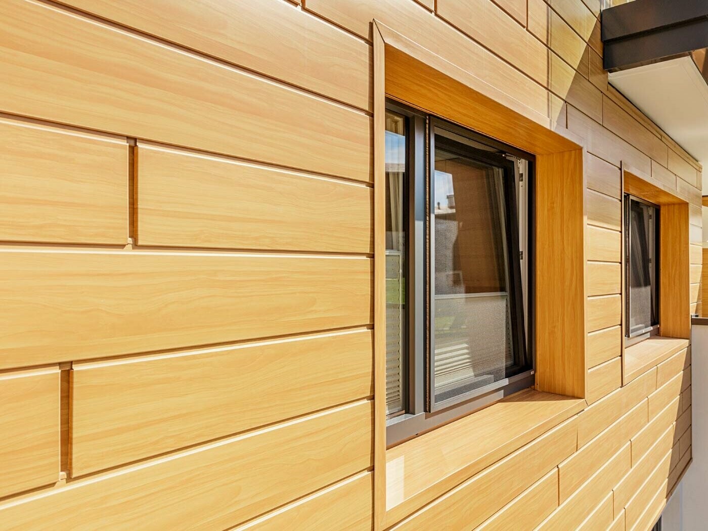 Surface de façade en aluminium avec les Sidings PREFA en aspect bois avec encadrement de fenêtre ;
