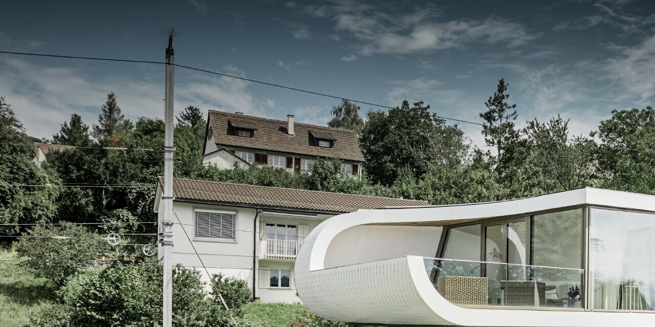 Modernissima casa unifamiliare progettata dall'architetto di Zurigo Camenzind; una fascia ricurva collega i singoli piani. Le curvature sono state rivestite con la scandola PREFA in bianco puro. La casa ha numerose ampie vetrate, che rendono l'intero ambiente particolarmente arioso.