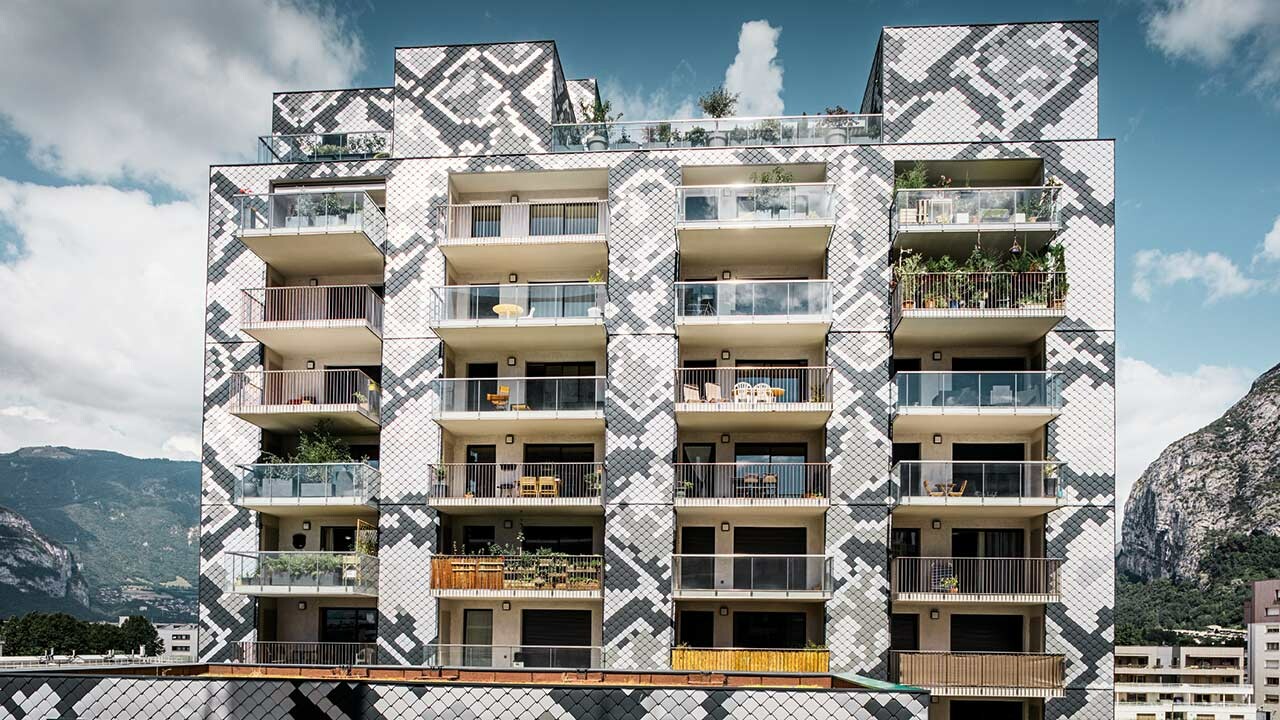 Frontale Aufnahme des Wohnhauses Le Python in Grenoble mit vielen Balkonen und einer Aluminiumfassade von PREFA, die Wandrauten ergeben ein Muster ähnlich das einer Schlange mit den Farbtönen anthrazit, hellgrau, naturblank und silbermetallic
