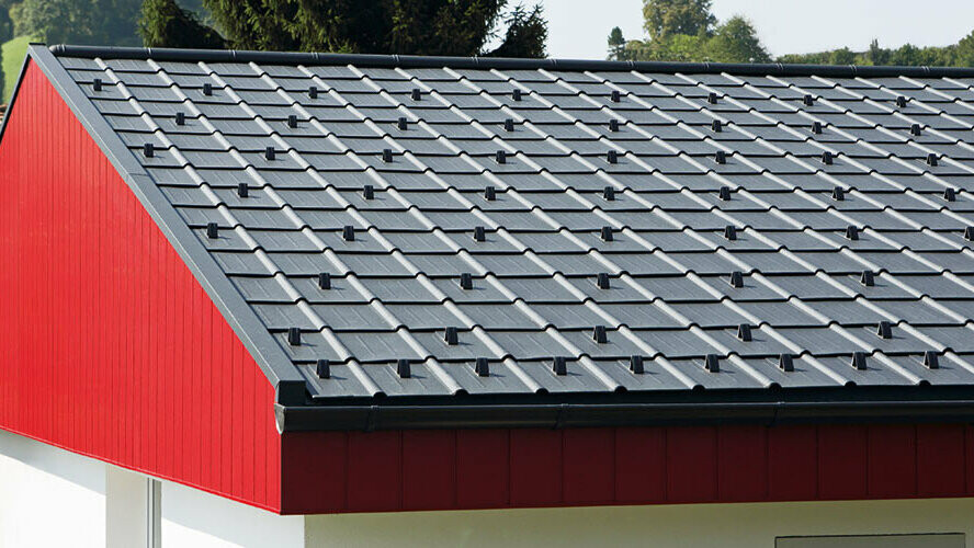 Giebelverkleidung in Rot mit PREFA Aluminium Siding, vertikal verlegt. Am Dach wurde die PREFA Dachplatte in P.10 Anthrazit verlegt.