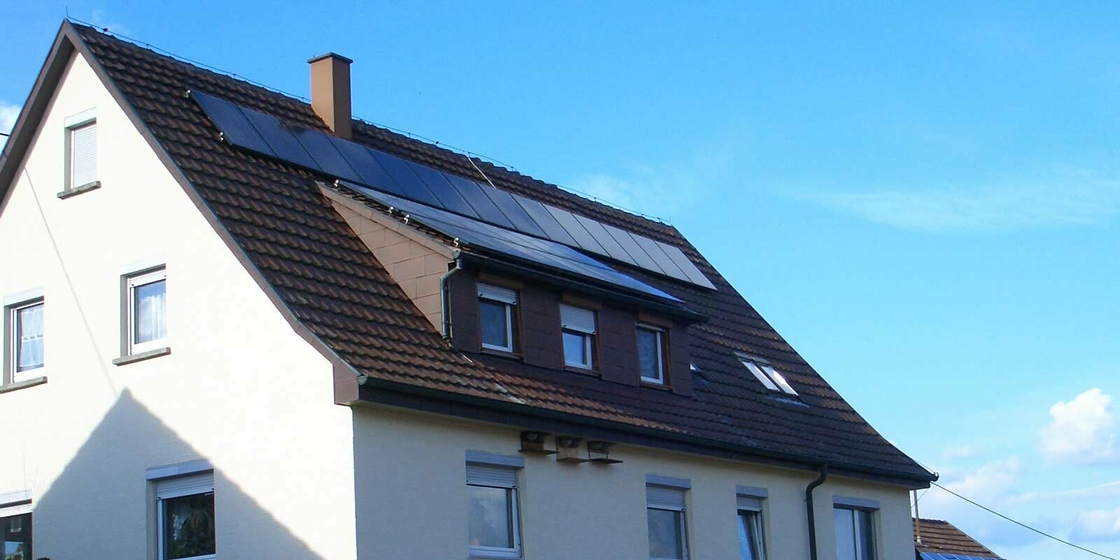 Maison individuelle avec toit en tuiles nécessitant une rénovation. Le toit est pourvu d’une lucarne ainsi que d’une installation photovoltaïque.
