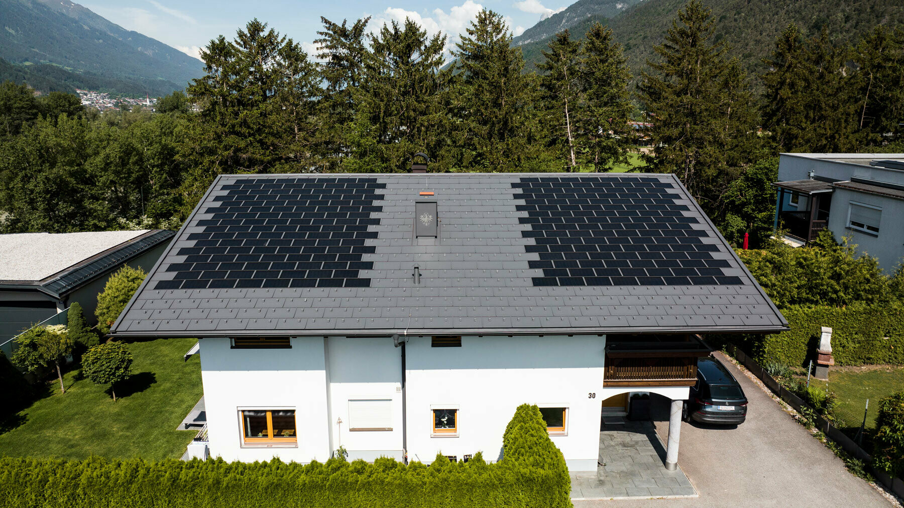 La photo montre une maison individuelle recouverte avec la tuile solaire PREFA petit format et R.16 couleur P.10 gris sombre dans un environnement rural.