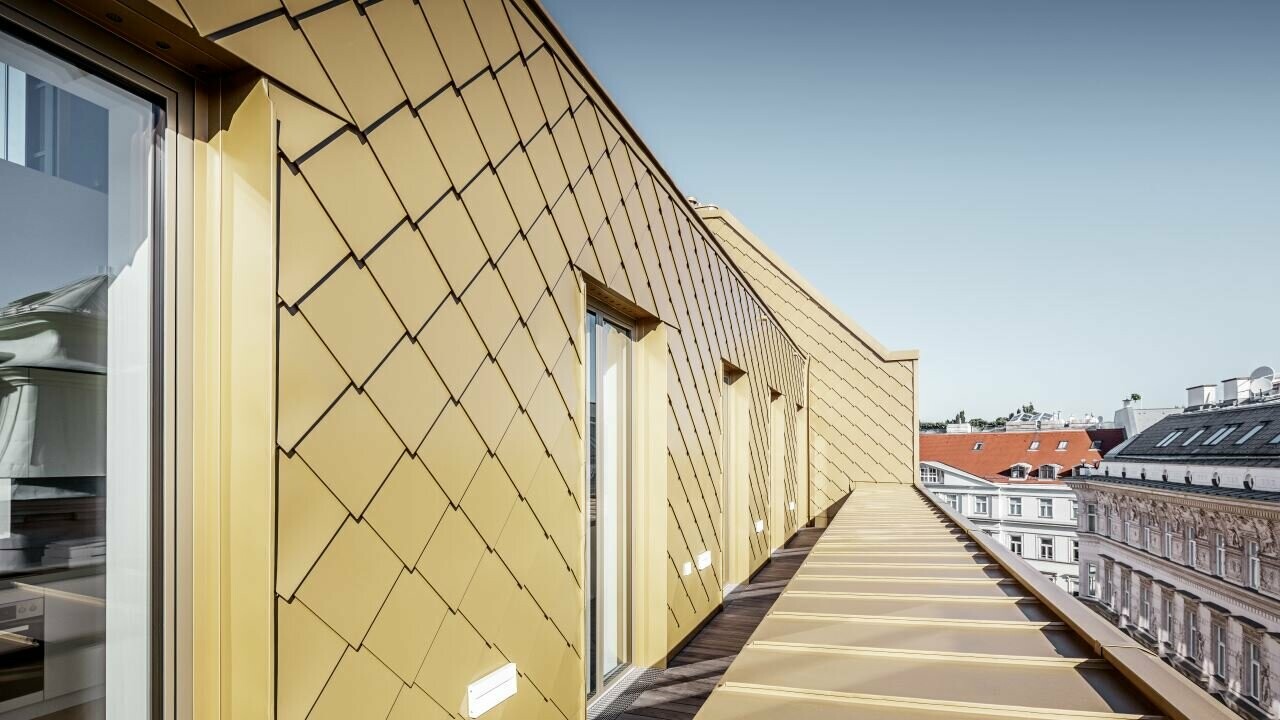 Vista laterale del rifacimento con attico realizzato con la Scaglia PREFA 29 × 29 in oro perlato