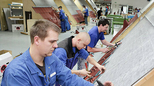 Spengler üben in der PREFA Academy an Dachmodellen die richtige Verlegung von PREFA Produkten.