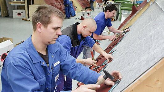 Spengler üben in der PREFA Academy an Dachmodellen die richtige Verlegung von PREFA Produkten.
