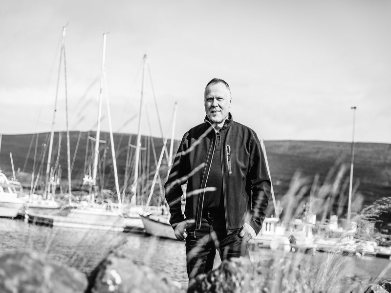 [Translate to italiano:] Der isländische Architekt Tryggvi Tryggvason steht im Freien vor einer Landschaft. Im Hintergrund sind Segelschiffe zu sehen.