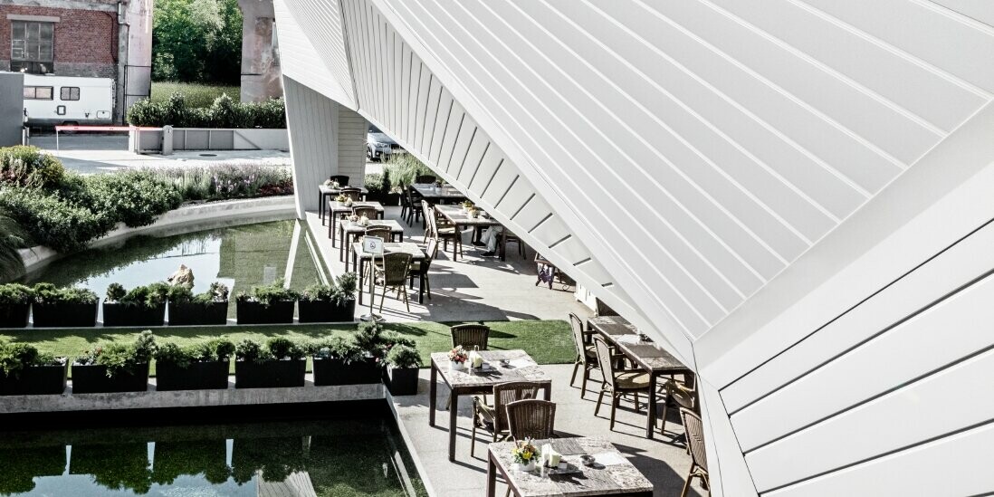 Gastgarten des Restaurants Mimama in Budapest mit der 3D-Fassade bekleidet mit dem PREFA Sidings in Prefaweiß.