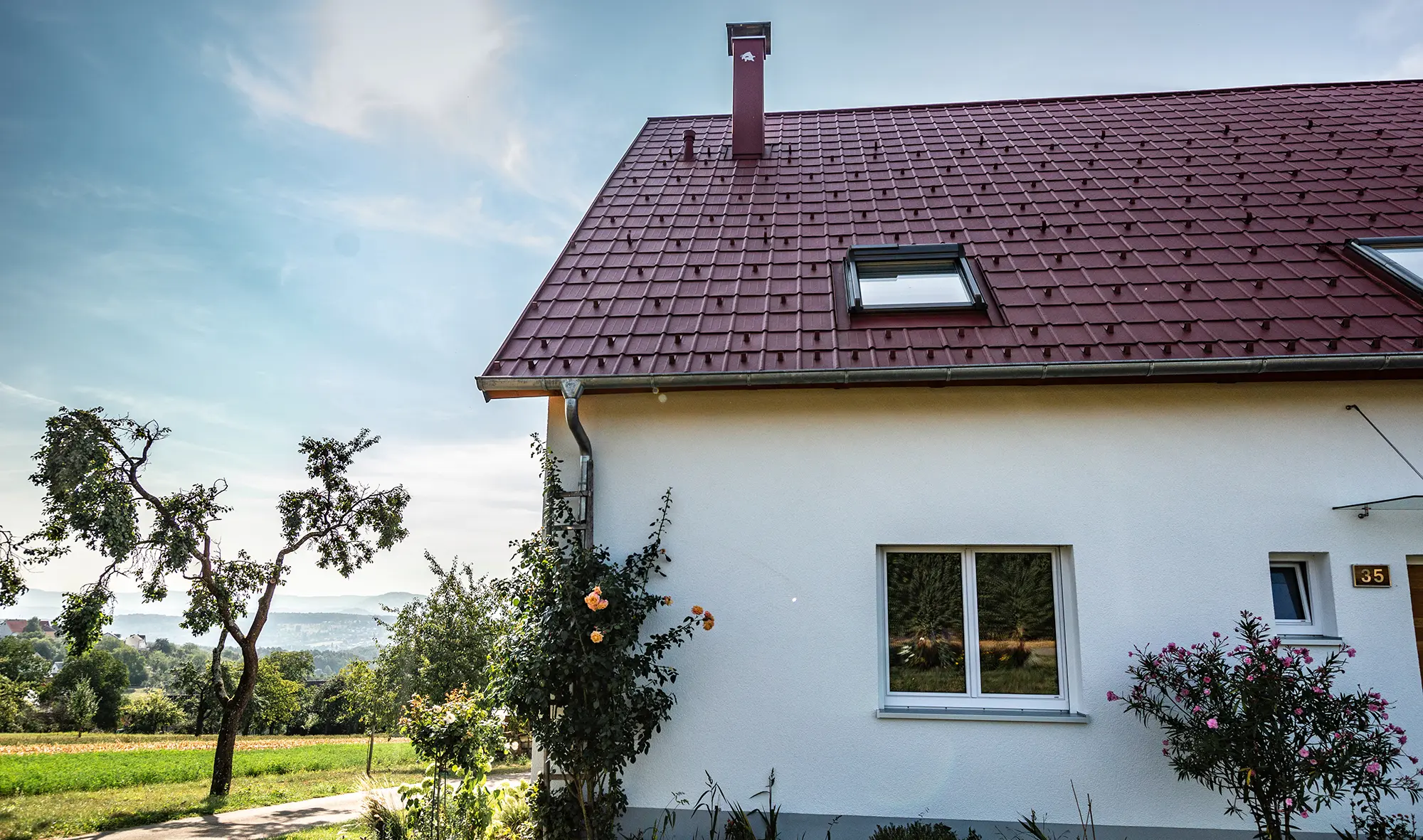 Häuschen am Land, neu saniertes Dach mit PREFA Dachplatte in Oxydrot, Dachfenster und Kamineinfassung.