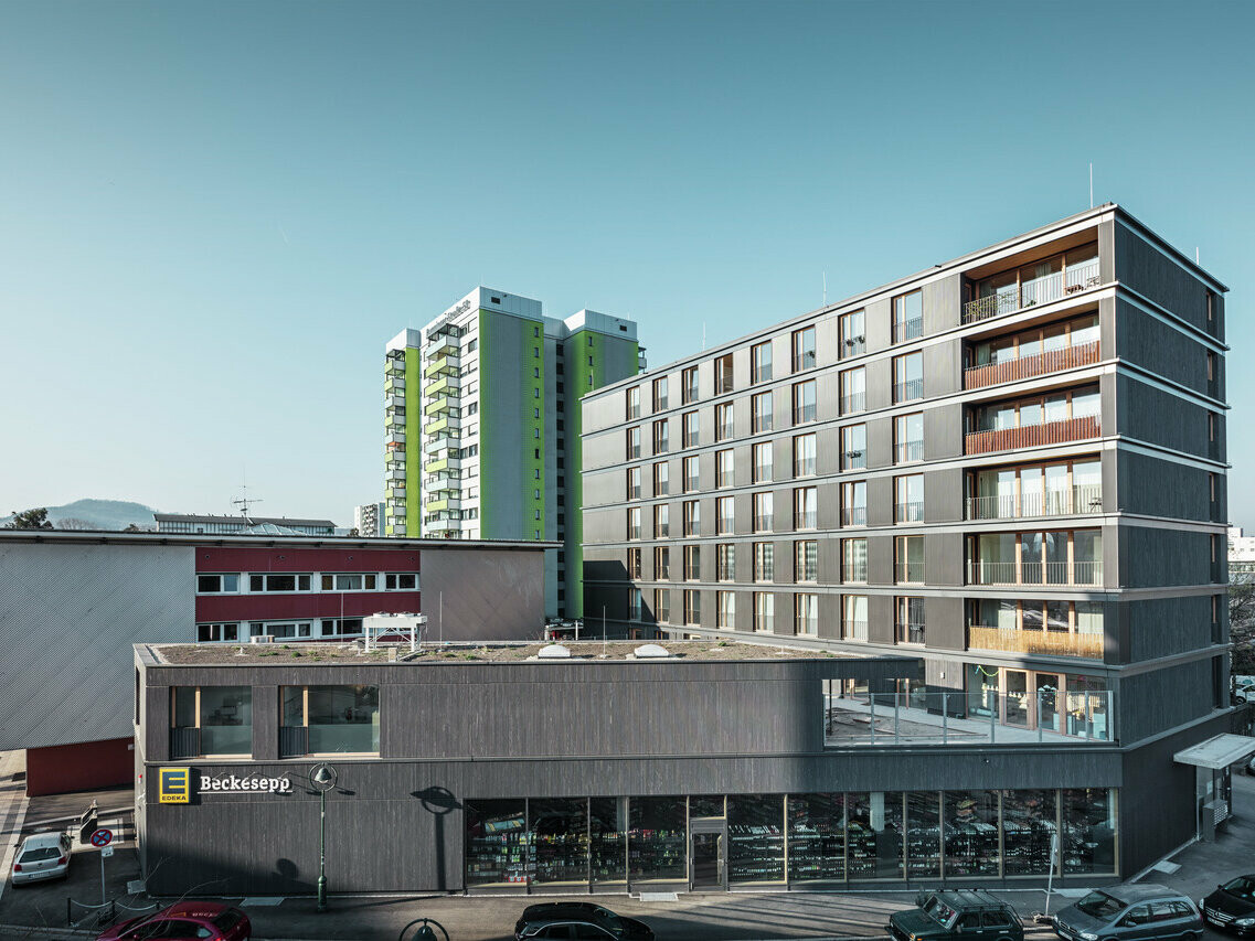 Vue du bâtiment multifonctionnel gris noir Buggi 52 et de son environnement bâti depuis la rue. 