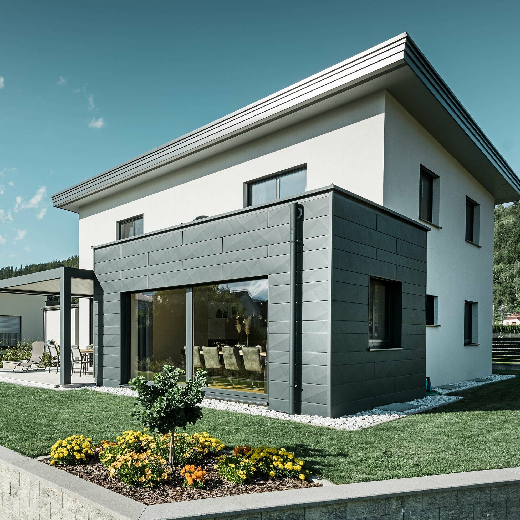 Einfamilienhaus mit Zubau, der Zubau ist mit einer PREFA Aluminium-Fassade verkleidet, das Flachdach wird mit Hilfe der PREFA Speiereinmündung und PREFA Ablaufrohr in P.10 Anthrazit entwässert,
