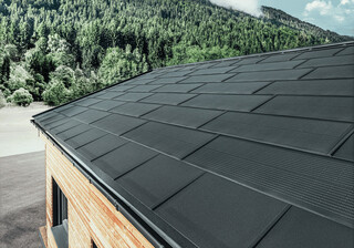 Tuile solaire PREFA grand format, combinée à la R.16 en noir, gouttière et façade en mélèze