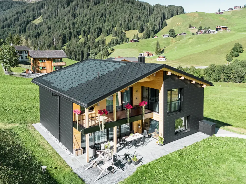 L'elegante casa unifamiliare nella zona collinare di Ascharina (Svizzera) mostra come l'alluminio e il legno possano essere perfettamente combinati.I robuste doghe per facciate PREFA Siding.X in P.10 nero si armonizzano con il tetto in tegole fotovoltaiche PREFA e tegole R.16 dello stesso colore. La pelle in alluminio di lunga durata protegge l'edificio in modo affidabile dalle sfide del clima alpino.