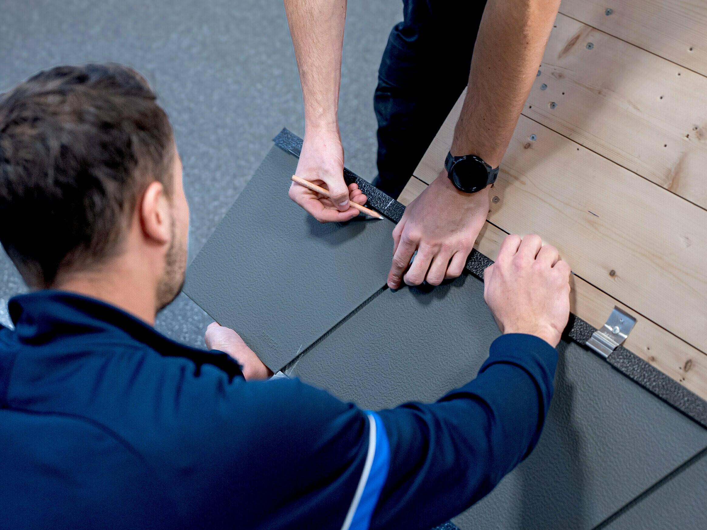 Dans la PREFA Academy, le formateur PREFA montre à un participant comment poser correctement les produits PREFA. 