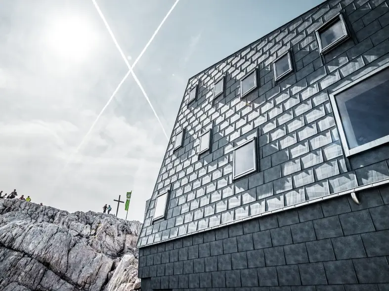 seitliche Ansicht der Seethalerhütte auf 2.740 Metern Höhe vor blauem Himmel, verkleidet mit PREFA Dach- und Fassadenpaneelen FX.12 in P.10 Steingrau