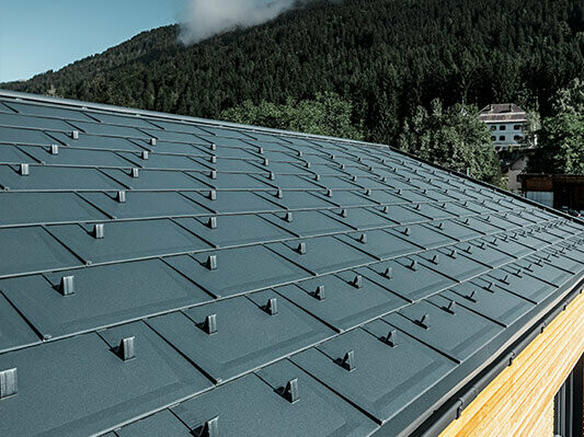 Detailansicht der neuen Dachplatte R.16 aus Aluminium von PREFA in anthrazit mit Holzfassade
