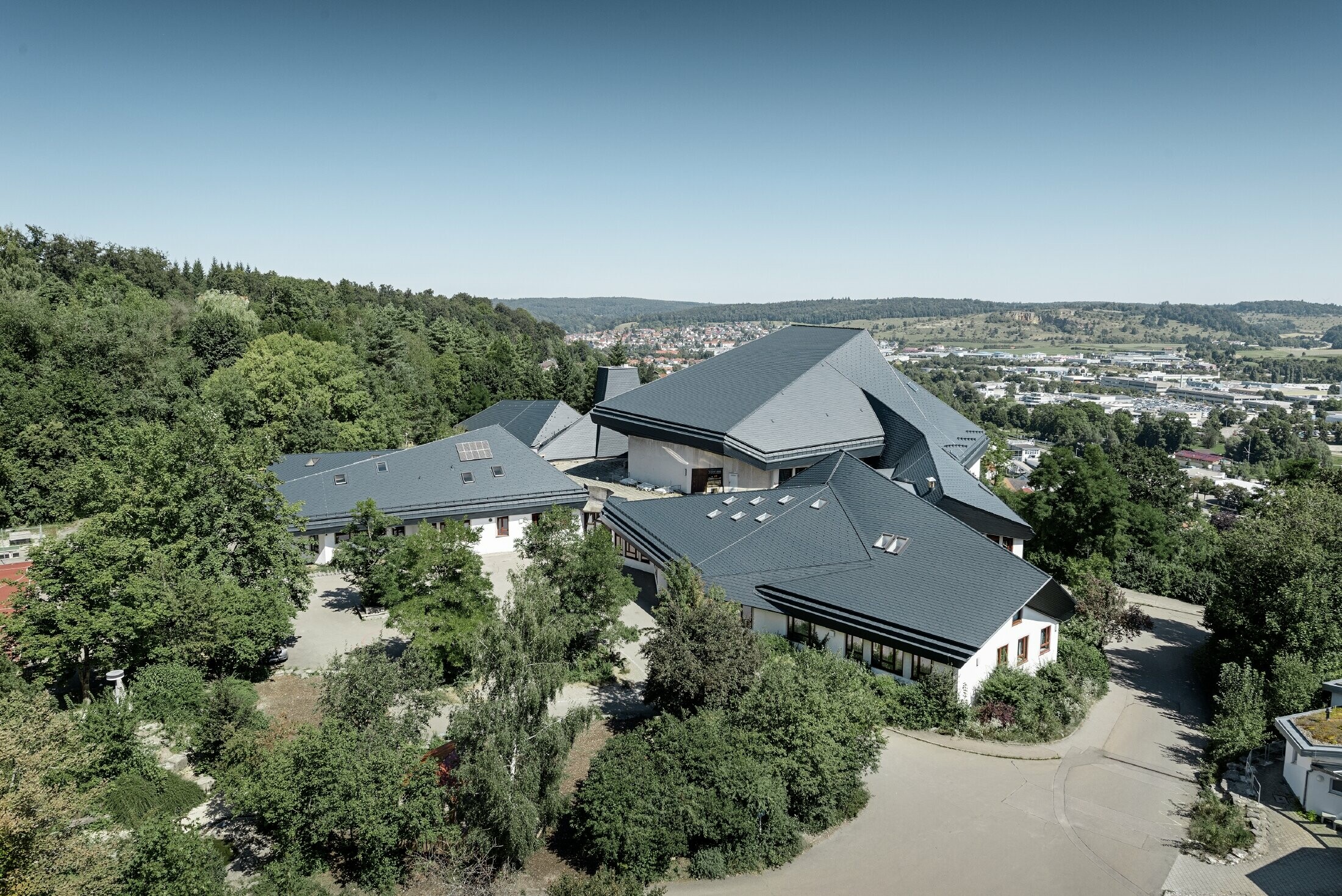 Scuola Waldorf a Heidenheim con copertura ristrutturata, la superficie di copertura ampia con diverse pendenze é stata rivestita con scandola PREFA in antracite