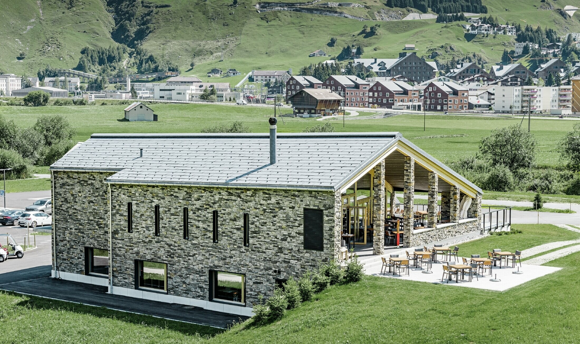 Modernes Club Haus des Golfplatzes in Andermatt mit Steinfassade und PREFA Dachpaneel FX.12 aus Aluminium in steingrau