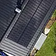 Vista dall'alto di un tetto PREFALZ con moduli solari montati, che mostra l'integrazione di moduli fotovoltaici vetro/vetro e superfici del tetto scoperte.