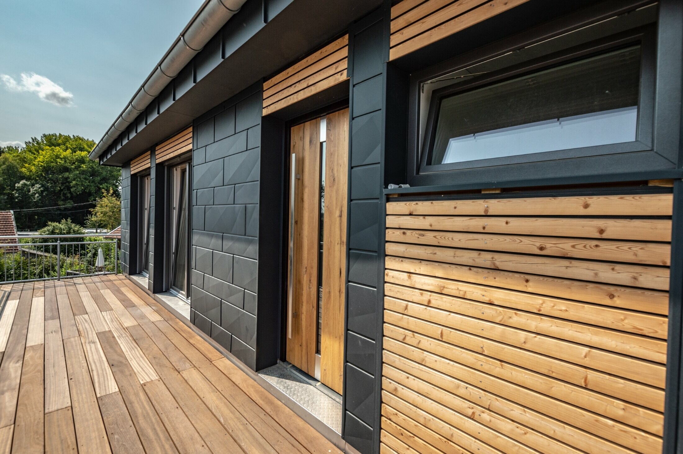 Design della facciata con combinazione di materiali alluminio - PREFA doga.X in antracite - e modanature orizzontali in legno.