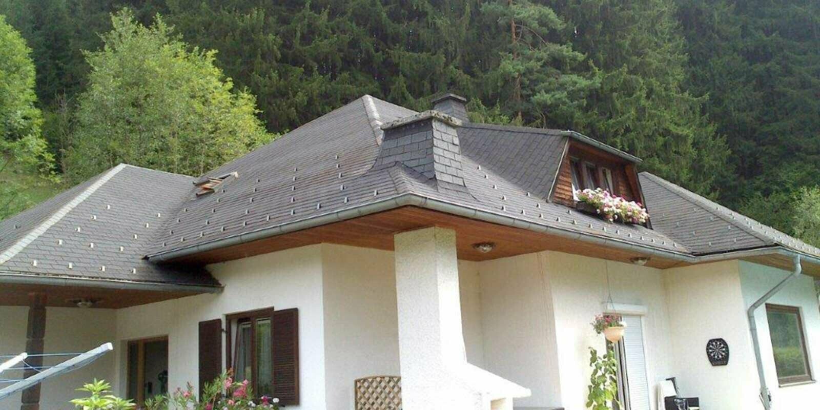 Maison individuelle avec toit à croupes avant la rénovation de toiture à l’aide de tuiles PREFA, lucarne en forme de trapèze incluse