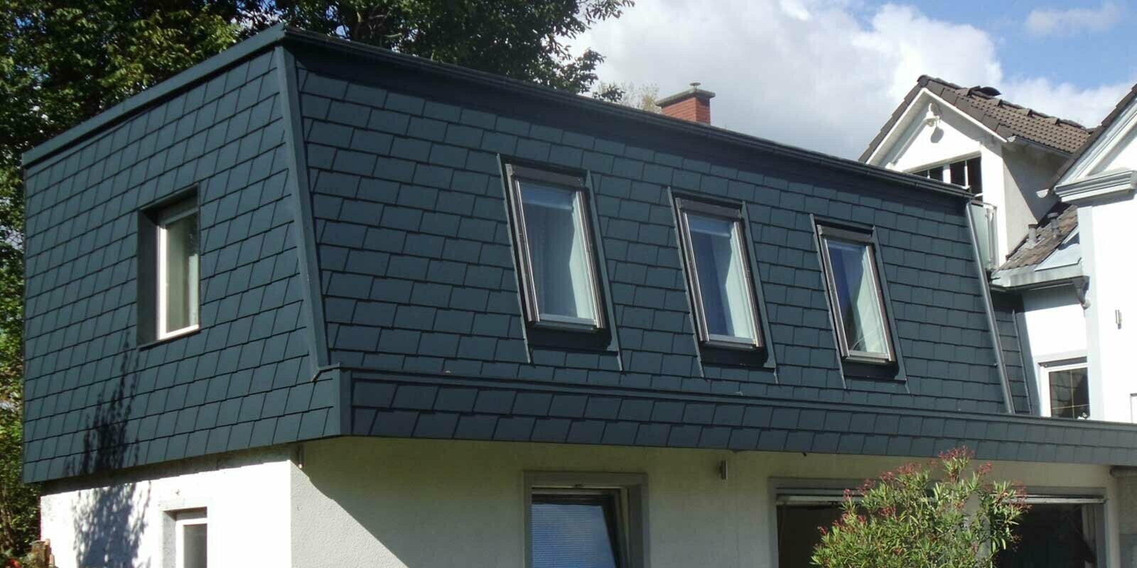 Copertura del tetto con scandole PREFA, moderna sopraelevazione color antracite con molte finestre