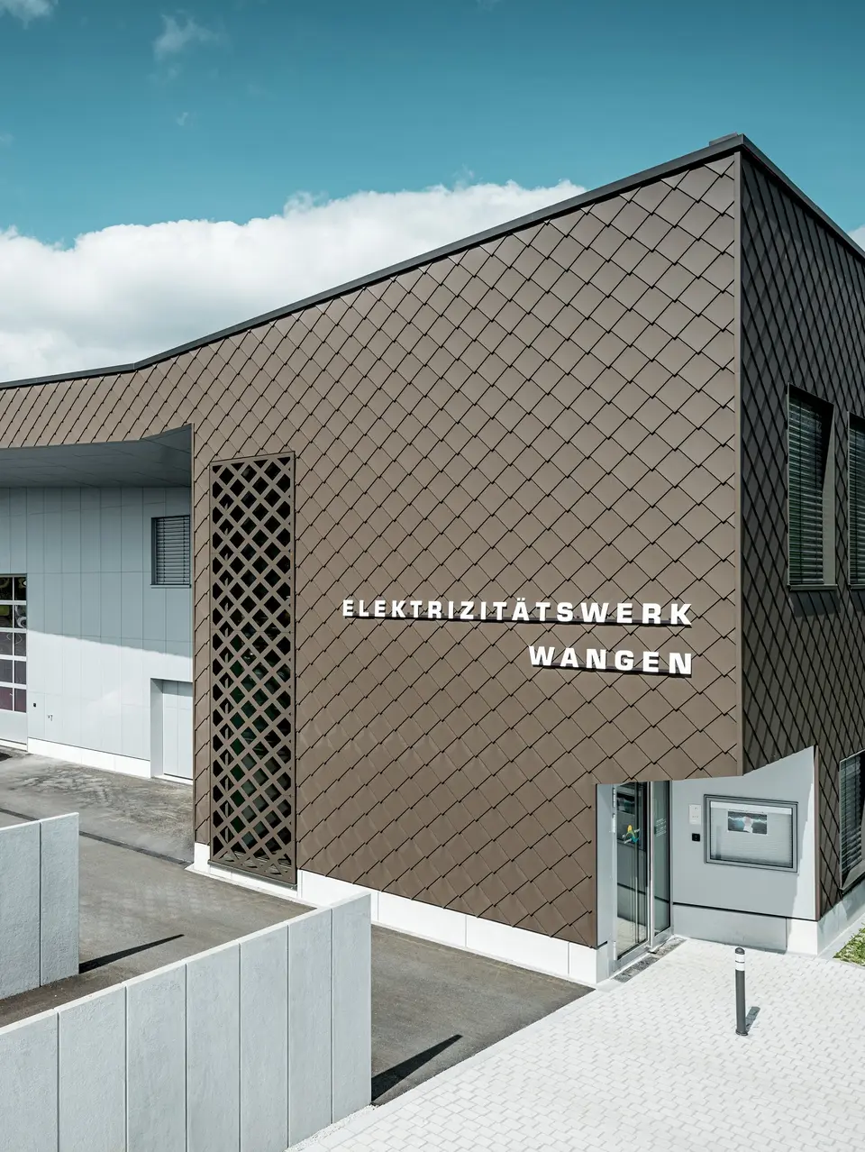 Modernes Feuerwehr- und Elektrizitätswerk in Wangen, Schweiz, mit markanter Gebäudehülle aus PREFA Wandrauten 29 × 29 in P.10 Braun. Die dynamische Rautenstruktur verleiht der Fassade Tiefe und eine unverwechselbare Optik. Aluminium Verbundplatten in P.10 Prefaweiß setzen helle Akzente. Die langlebigen PREFA Aluminiumprodukte überzeugen durch hohe Witterungsbeständigkeit, geringen Wartungsaufwand und maximale Gestaltungsfreiheit.