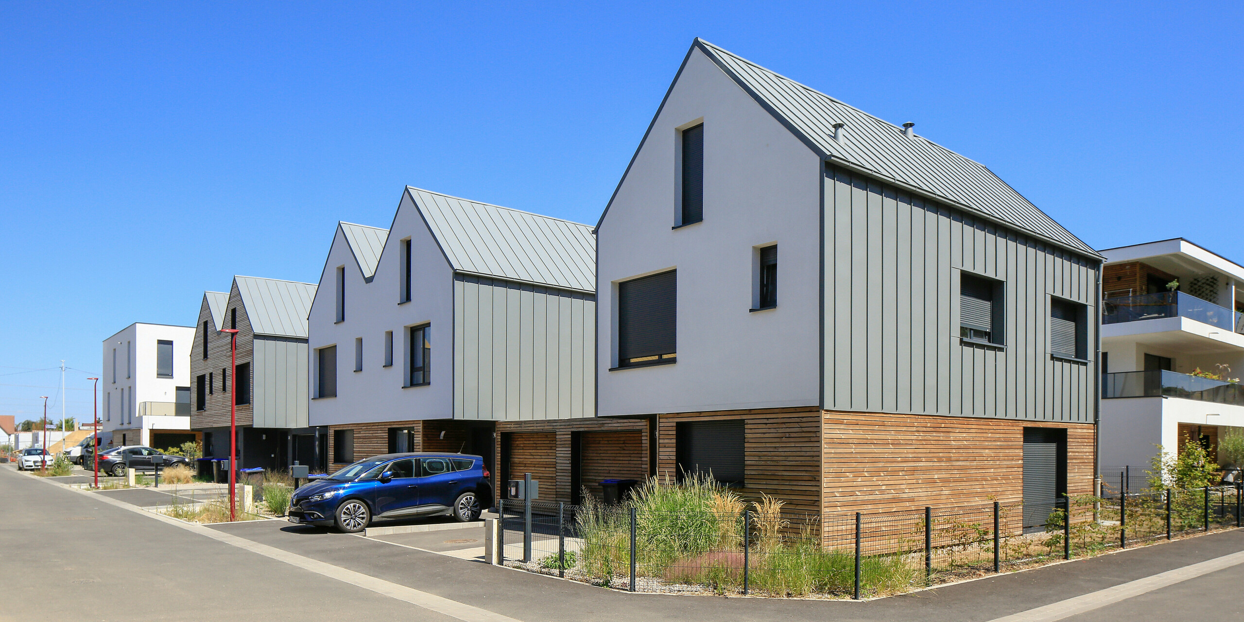 Le joint debout PREFALZ en gris souris s'étend sur les façades et les toits à pignon d'un lotissement mitoyen à Mundolsheim. Les coques uniformes du bâtiment en aluminium créent une image globale harmonieuse.