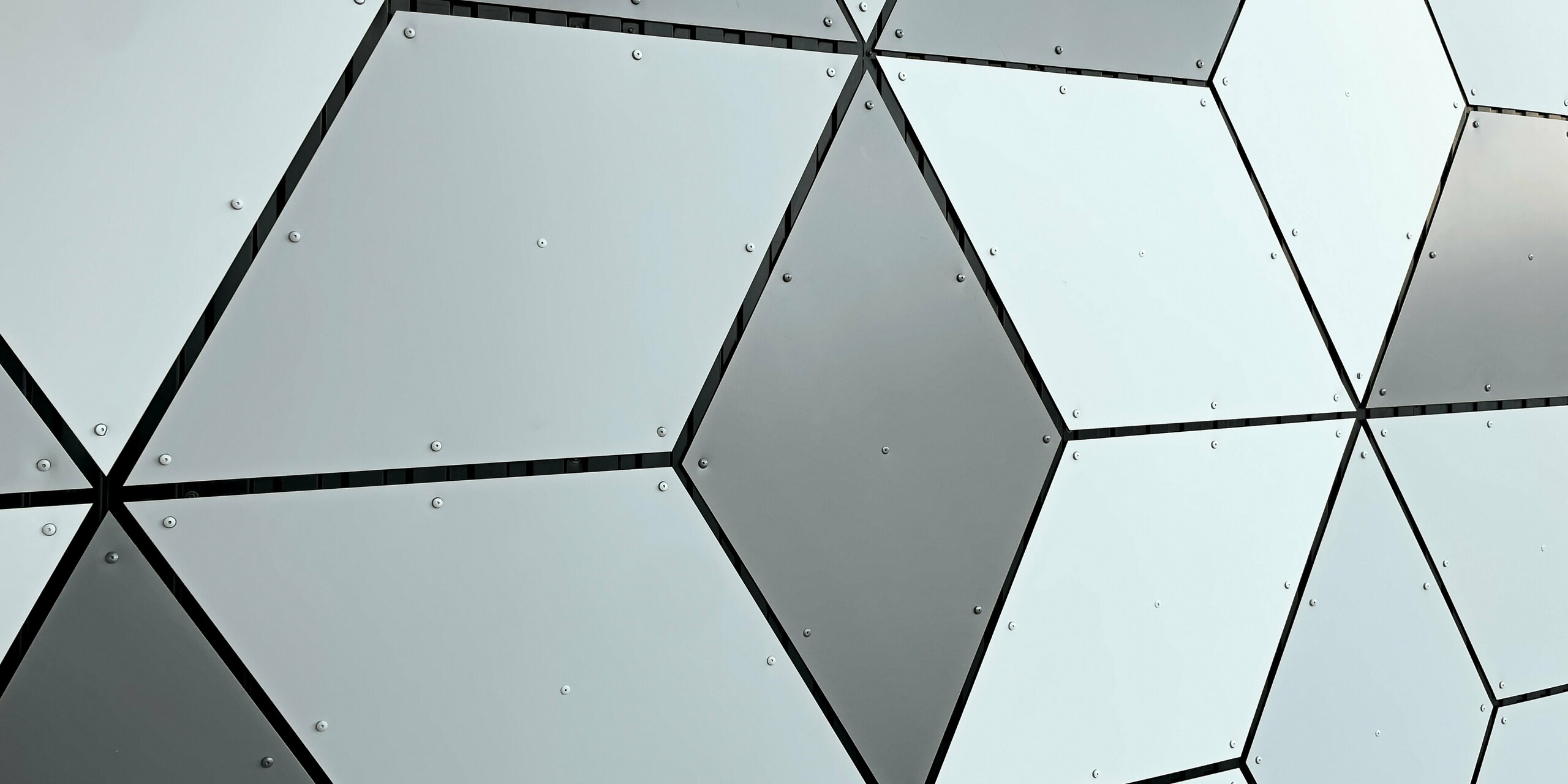 Detailaufnahme der Fassade der Seilbahnstation in Les Deux Alpes. Die PREFABOND Aluminium Verbundplatten sind in Rautenform angeordnet. Die faszinierende Kombination aus Weiß- und Grautönen erzeugt ein modernes, geometrisches Muster. Die solide Befestigung mit Schrauben unterstreicht die langlebige und widerstandsfähige Bauweise, die auch extremen Wetterbedingungen im Hochgebirge standhält.