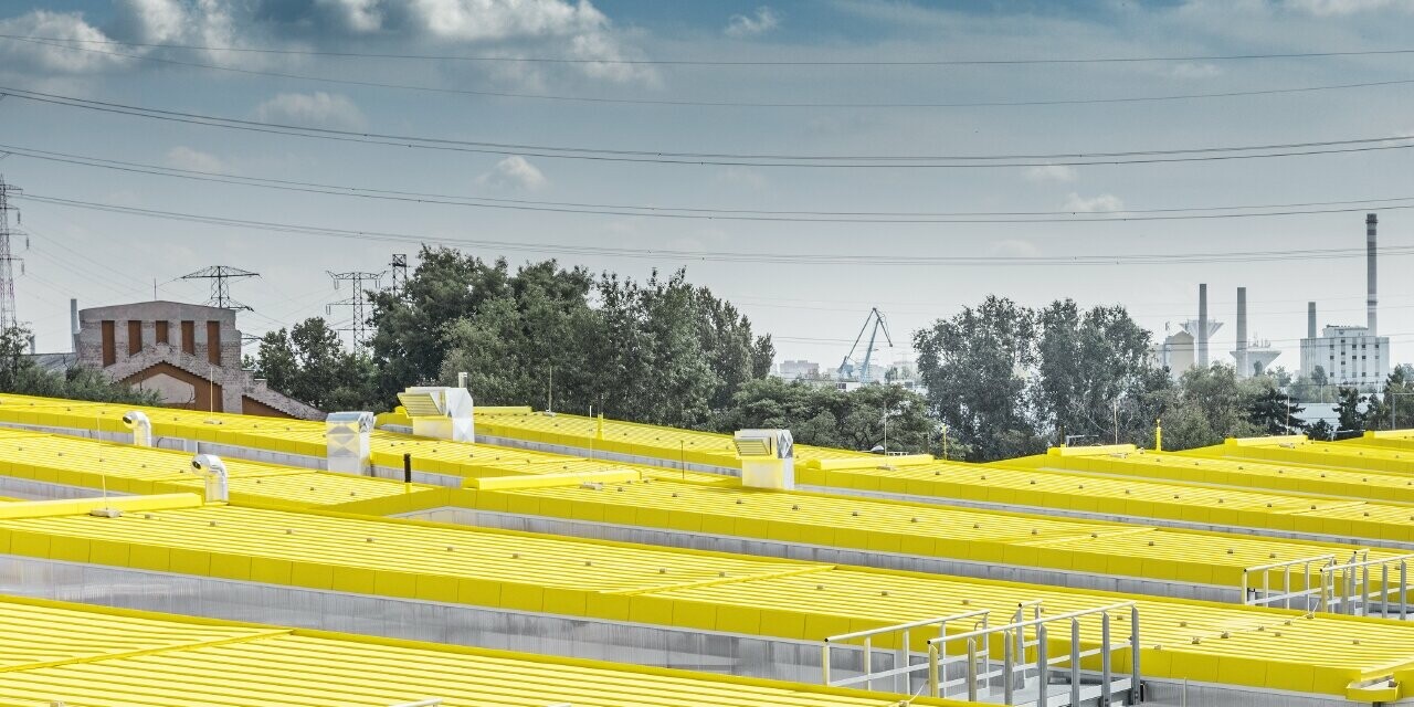 La forme du nouvel entrepôt de Budapest rappelle les tramways de la ville. Il a été habillé avec un toit à joint debout de PREFA couleur jaune signalisation, RAL 1023.