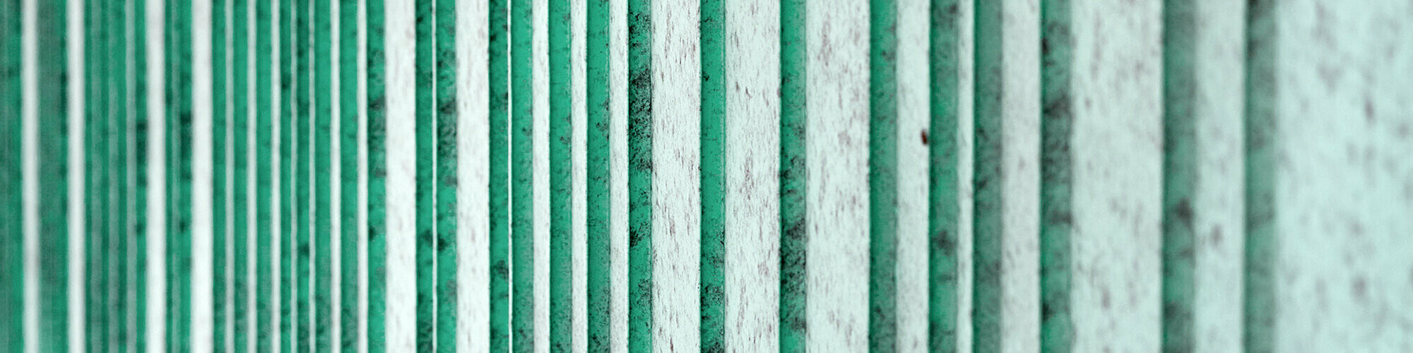 Detailansicht der patinagrünen Aluminium Fassade, rhythmisiert mit unterschiedlich breiten Scharen. Die Farbe erzeugt eine gesprenkelte Optik.