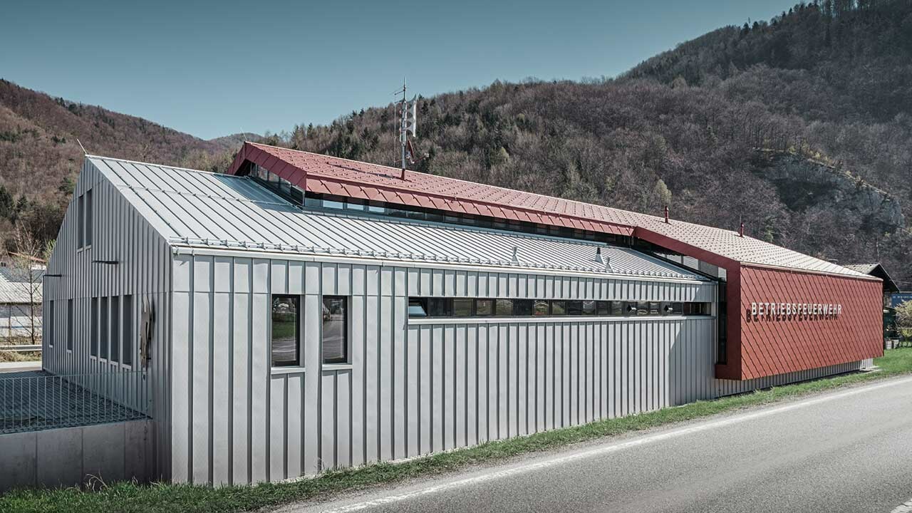 moderne Betriebsfeuerwehr der Firma Neuman mit gleichmäßigen Blechbahnen in silbermetallic und rotem Aludach und Alufassade mit der Wandraute von PREFA