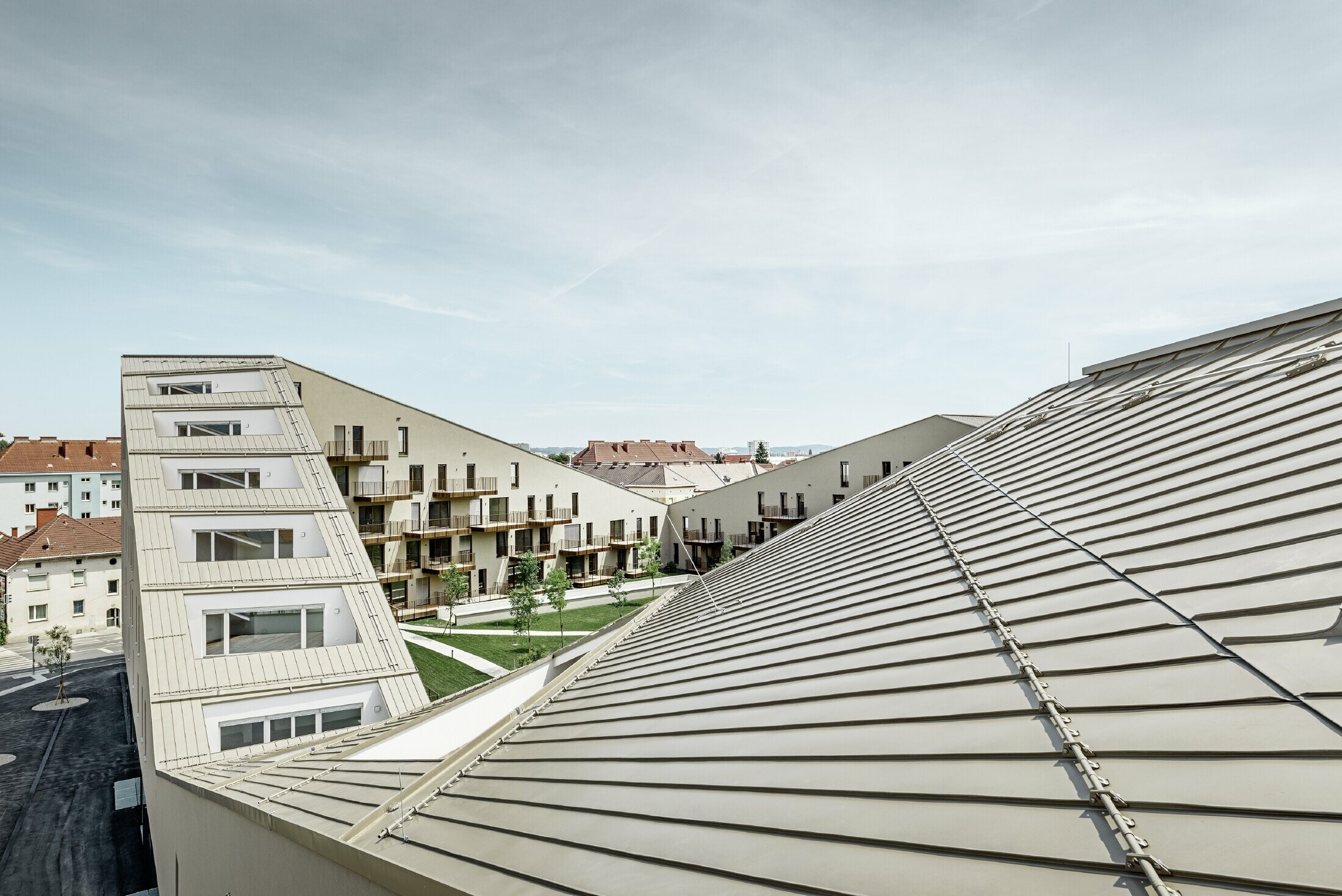 complesso residenziale di forma allungata a Graz con superfici di copertura piane e terrazze integrate e ampie vetrate con una copertura in Prefalz nel colore broncemetallic