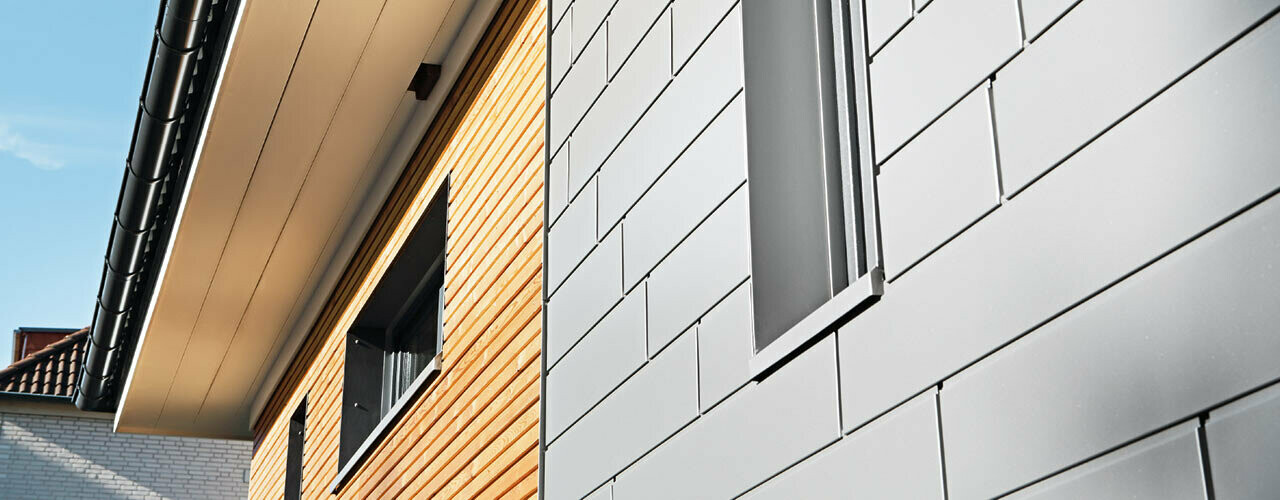 Combinazione di alluminio - doghe PREFA in grigio alluminio - con una facciata in legno. Posa orizzontale, fughe sfalsate.