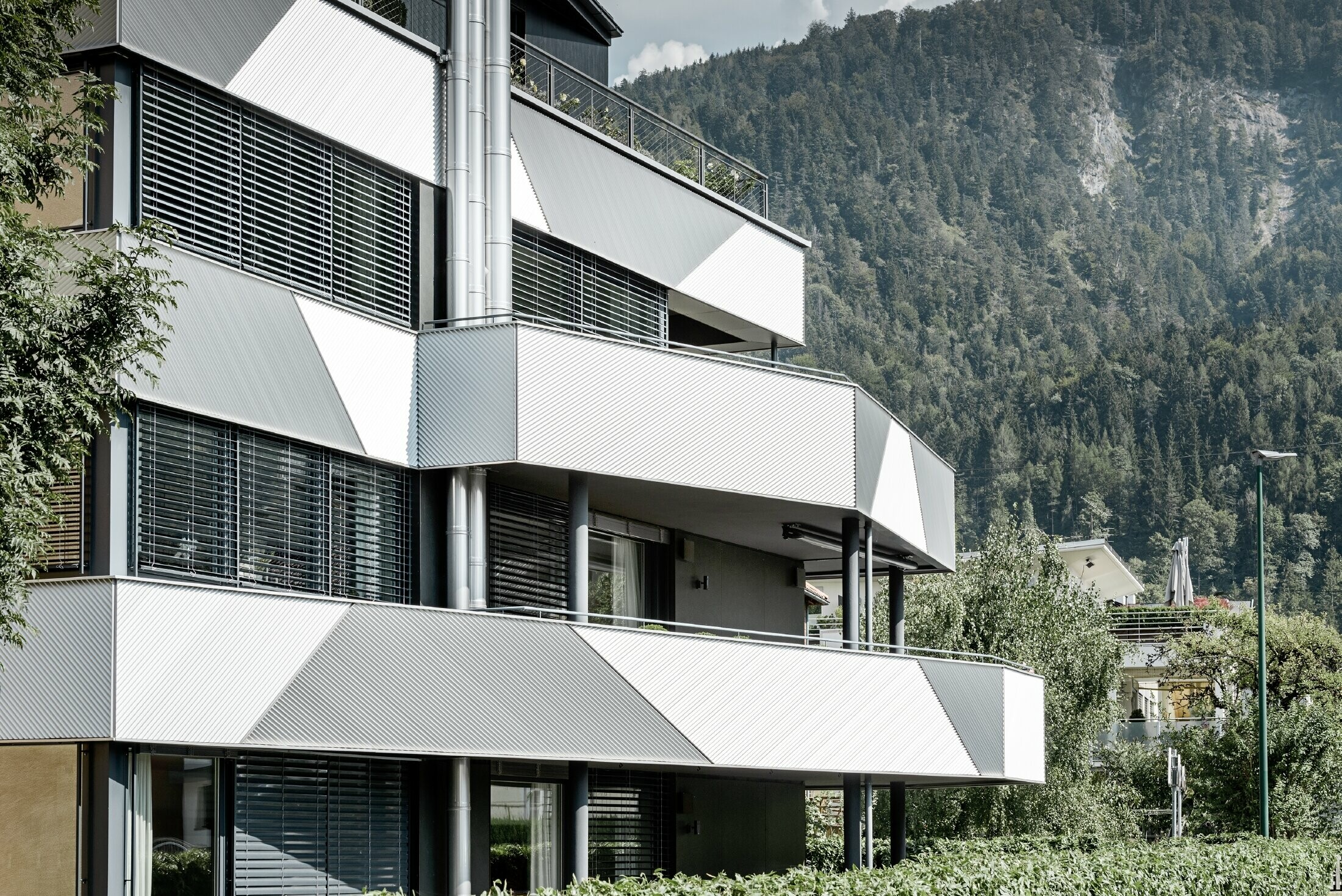 Design della facciata per un condominio con balcone e logge con il profilo a zeta PREFA con posa in diagonale.