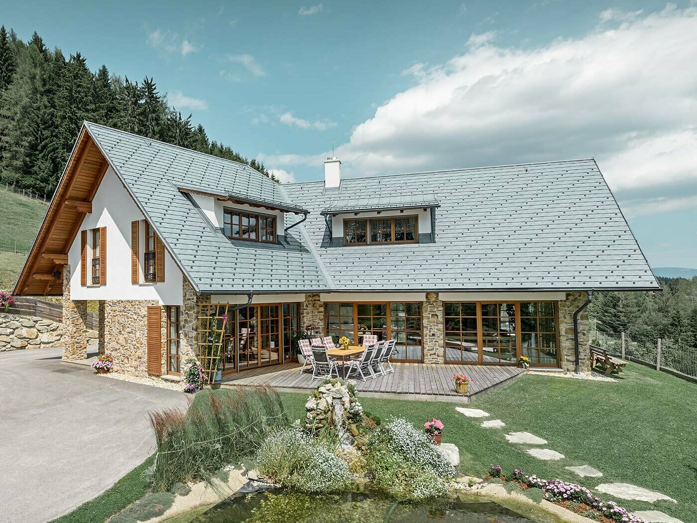 Einfamilienhaus mit Satteldach und zwei Gauben; Das Dach ist mit der PREFA Dachschindel aus Aluminium in Steingrau eingedeckt.